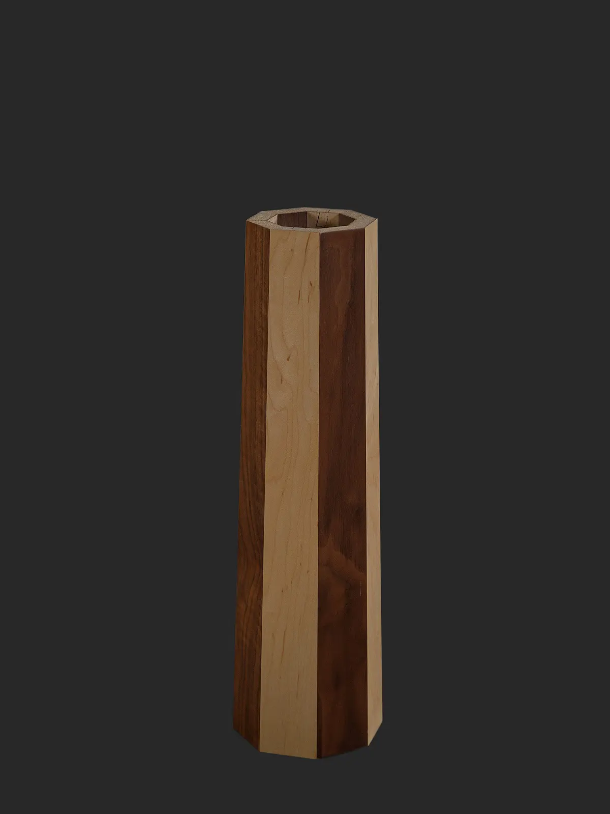 A tall wooden vase featuring a contemporary striped pattern in light and dark wood tones, set against a dark background.